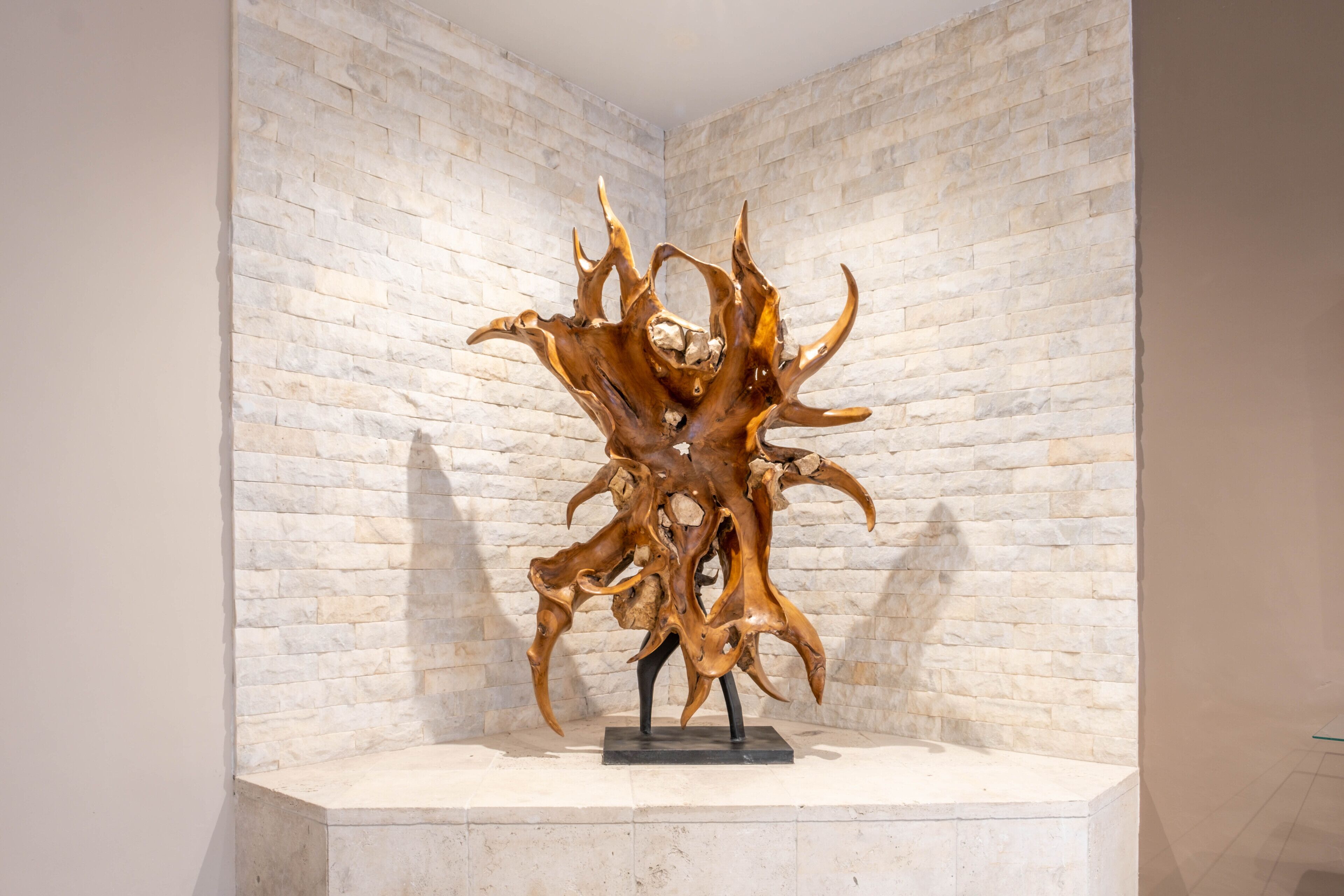 A sculpture on a pedestal against a white brick wall.