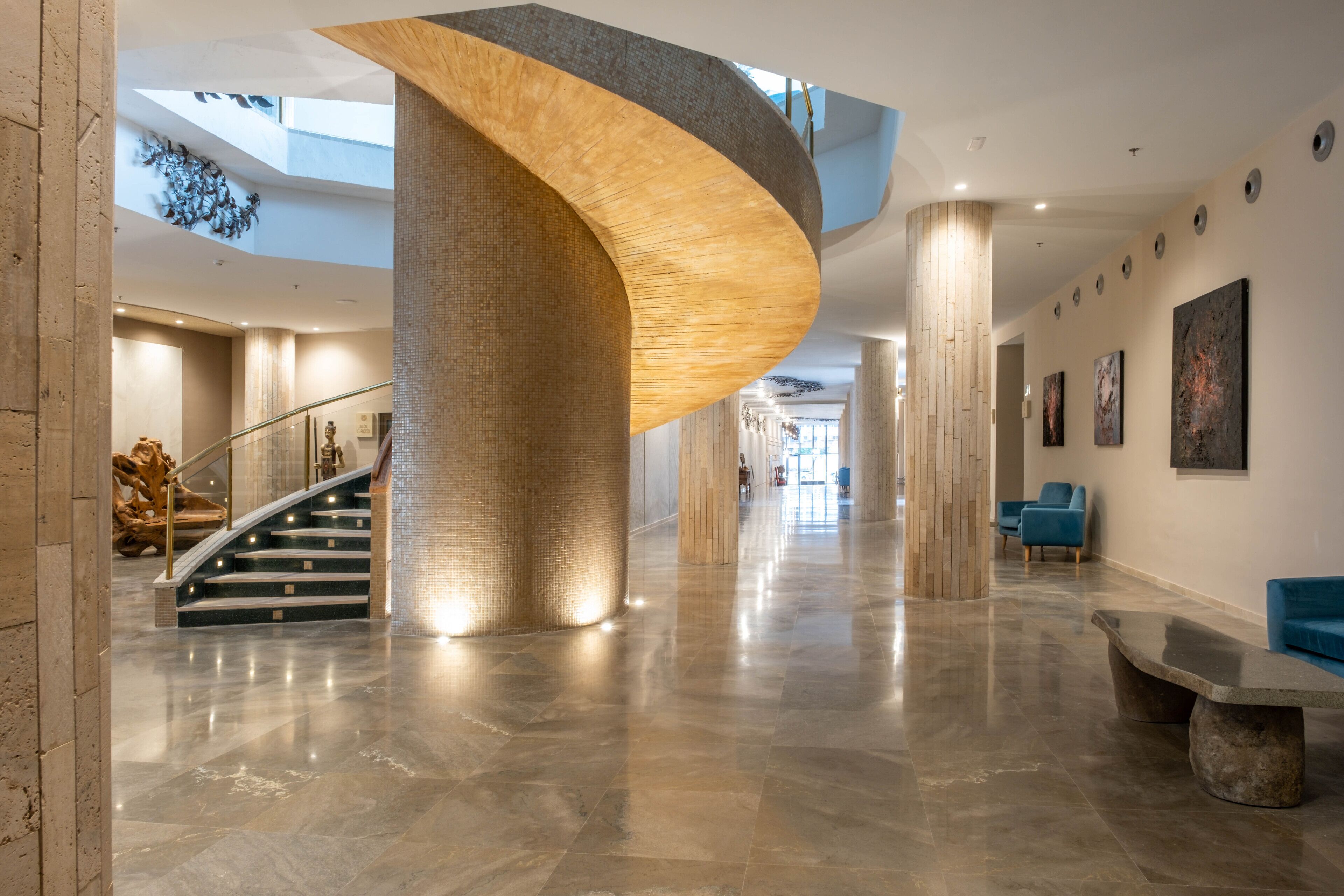 A spacious lobby with a curved wooden column, a staircase, and a seating area.