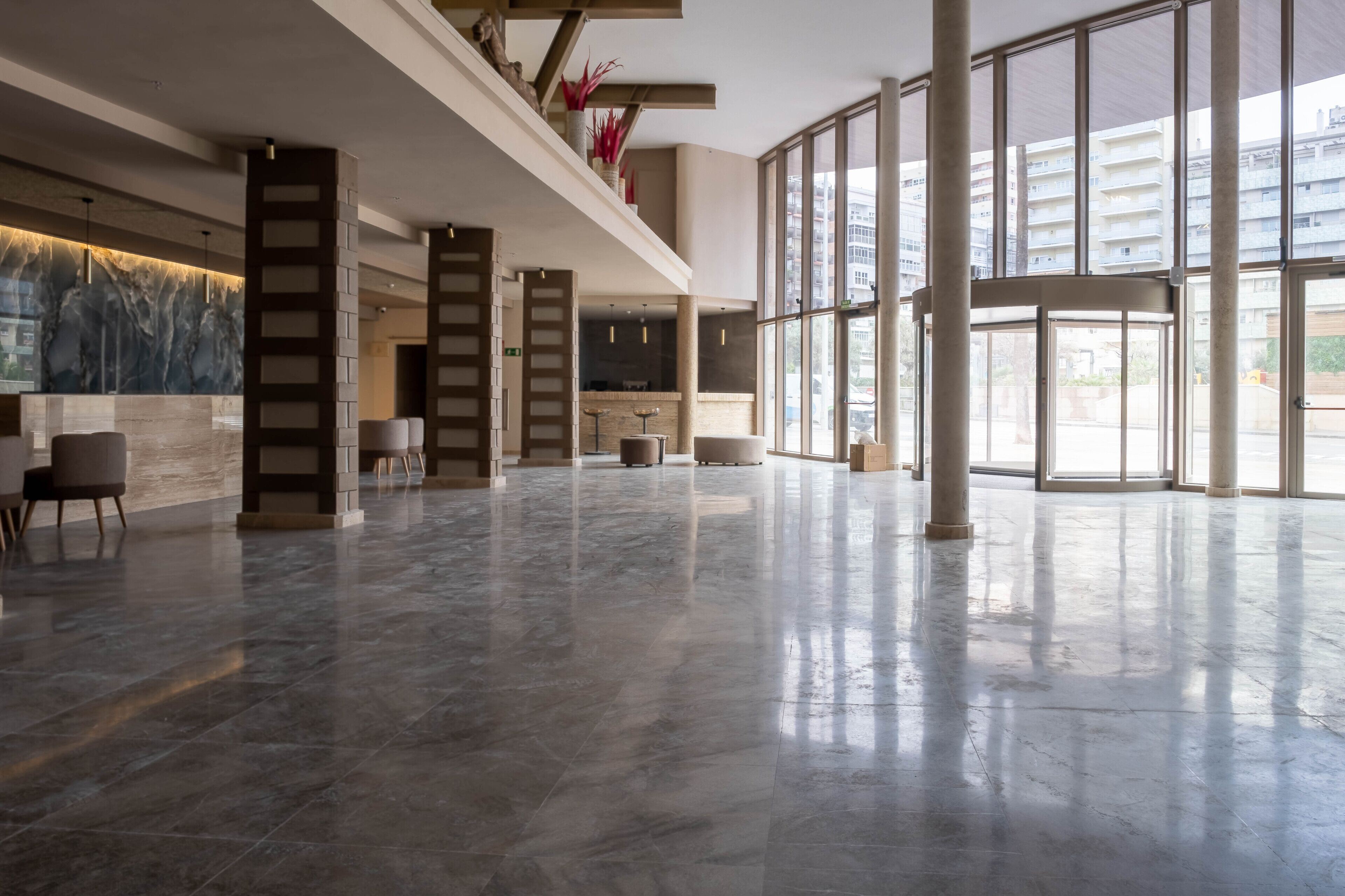 A spacious lobby with a marble floor, large windows, and a reception area with a modern design.