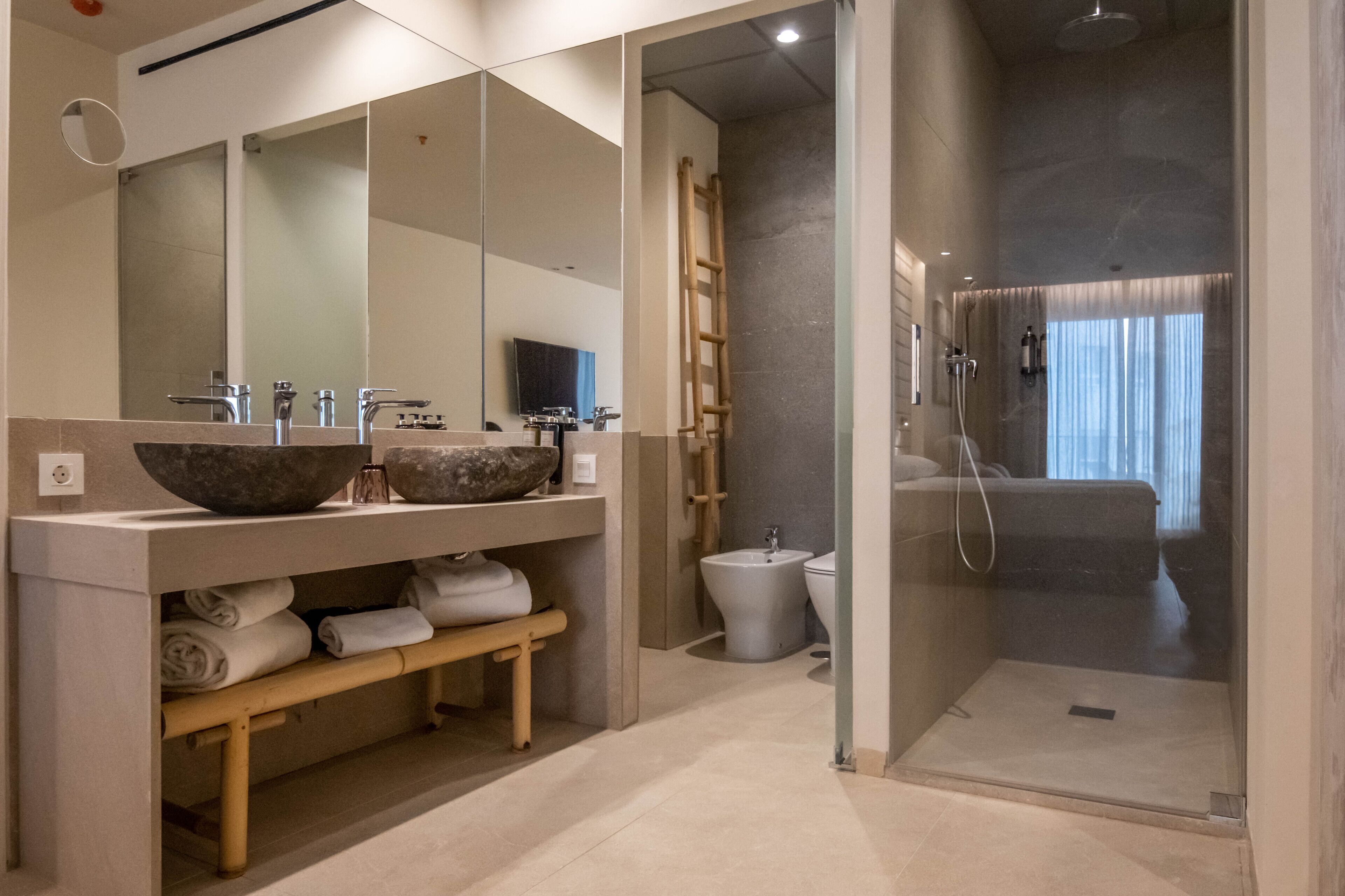 Ein modernes Badezimmer mit einem großen Spiegel, zwei Waschbecken, einem Bidet und einer Duschkabine.