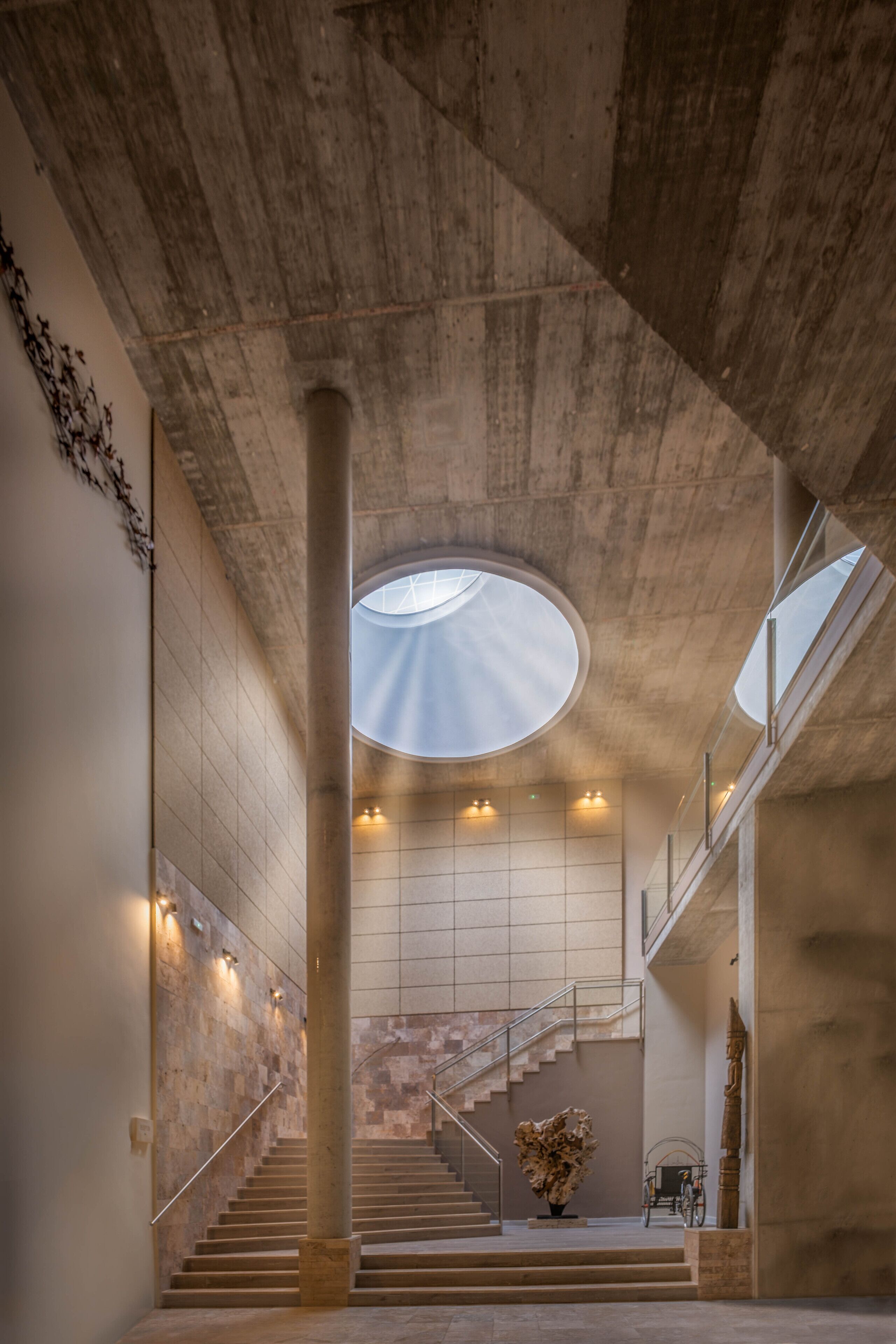 Un interior amplio con una escalera central, tragaluces y un diseño moderno.