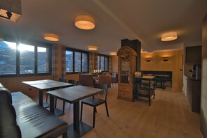 A restaurant with wooden tables and benches, large windows, and pendant lighting. - EVAL Grindelwald AG (Grindelwald)