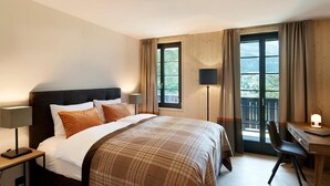 A hotel room with a bed, bedside lamps, a desk with a chair, and a balcony with curtains. - EVAL Grindelwald AG (Grindelwald)