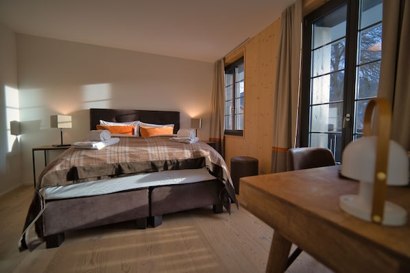 Une chambre d’hôtel avec un grand lit, un bureau en bois et une fenêtre avec des rideaux.