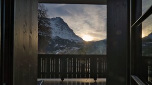 A balcony with a view of a snow-covered mountain and the sun setting in the background. - EVAL Grindelwald AG (Grindelwald)