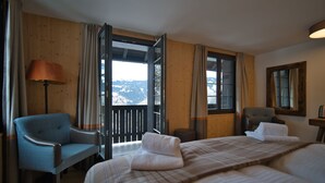 A hotel room with a bed, a chair, a lamp, and a view of mountains through the open door. - EVAL Grindelwald AG (Grindelwald)