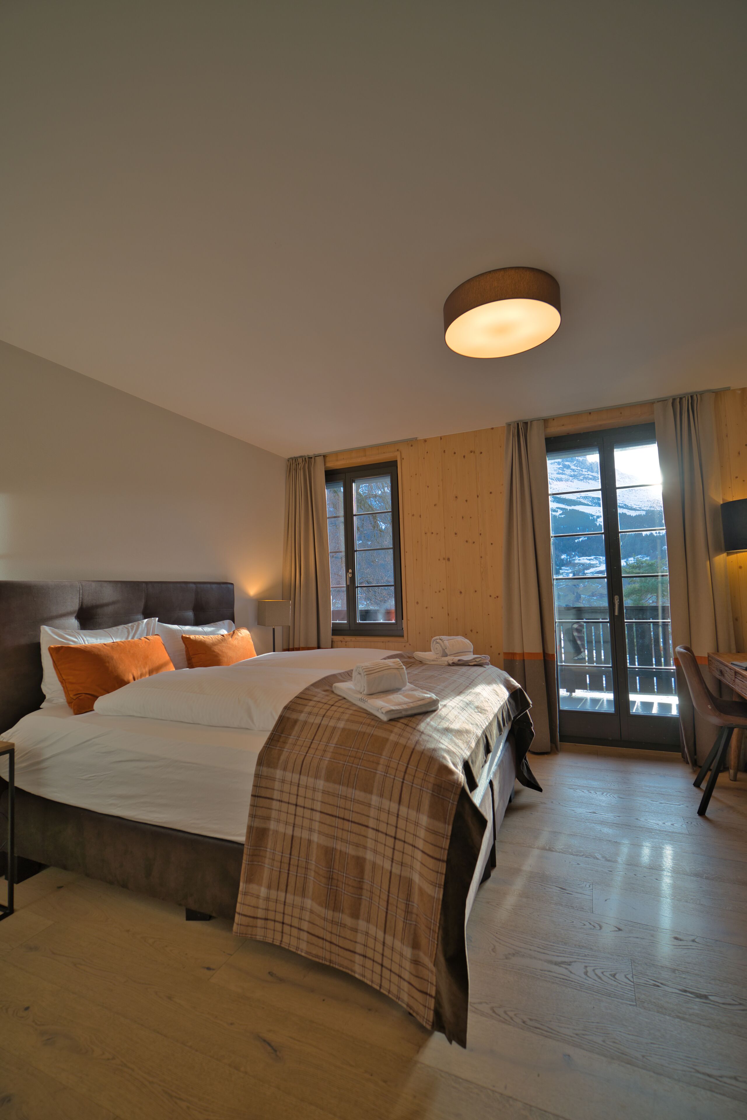 A hotel room with a large bed, a desk, and a view of the outdoors.