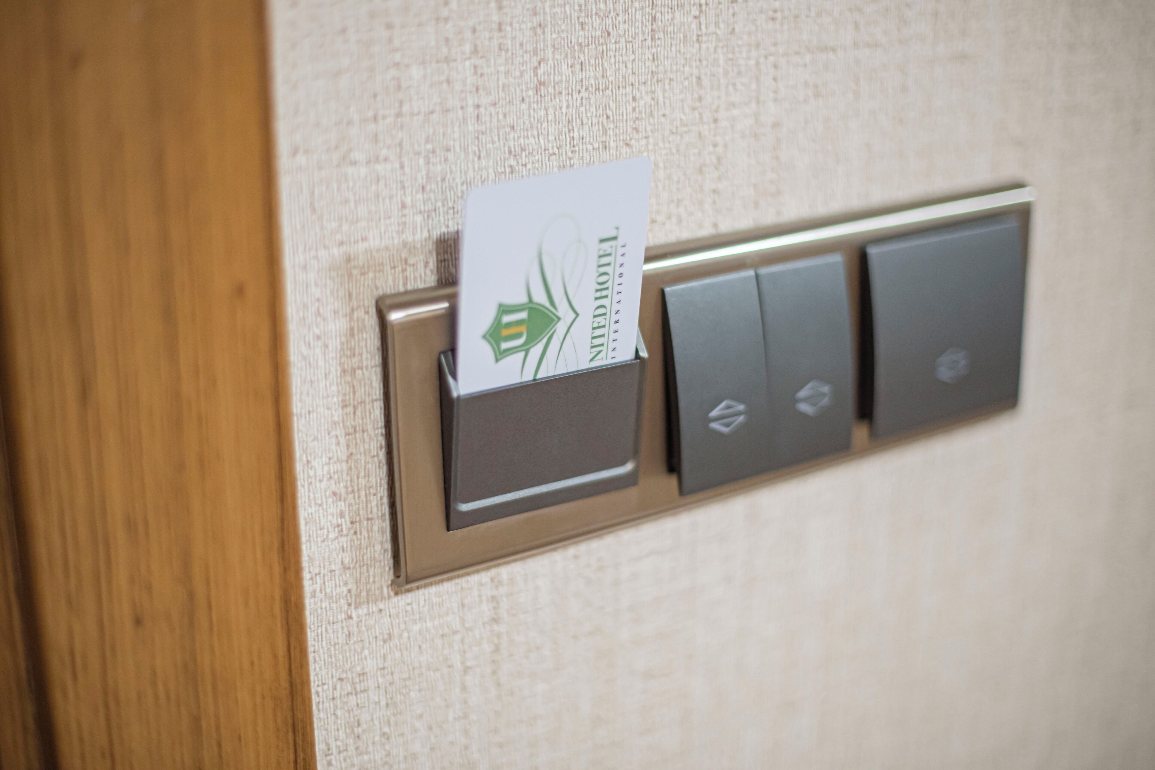 Un panneau de commande de chambre d’hôtel avec un lecteur de carte et trois boutons.