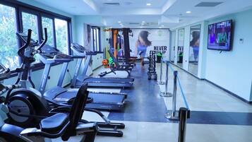 Un gimnasio con cintas de correr, elípticas y equipo de pesas.