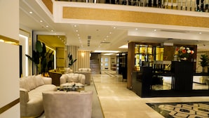 En rummelig lobby med siddeområde, receptionsdisk og trappe op til en etage.