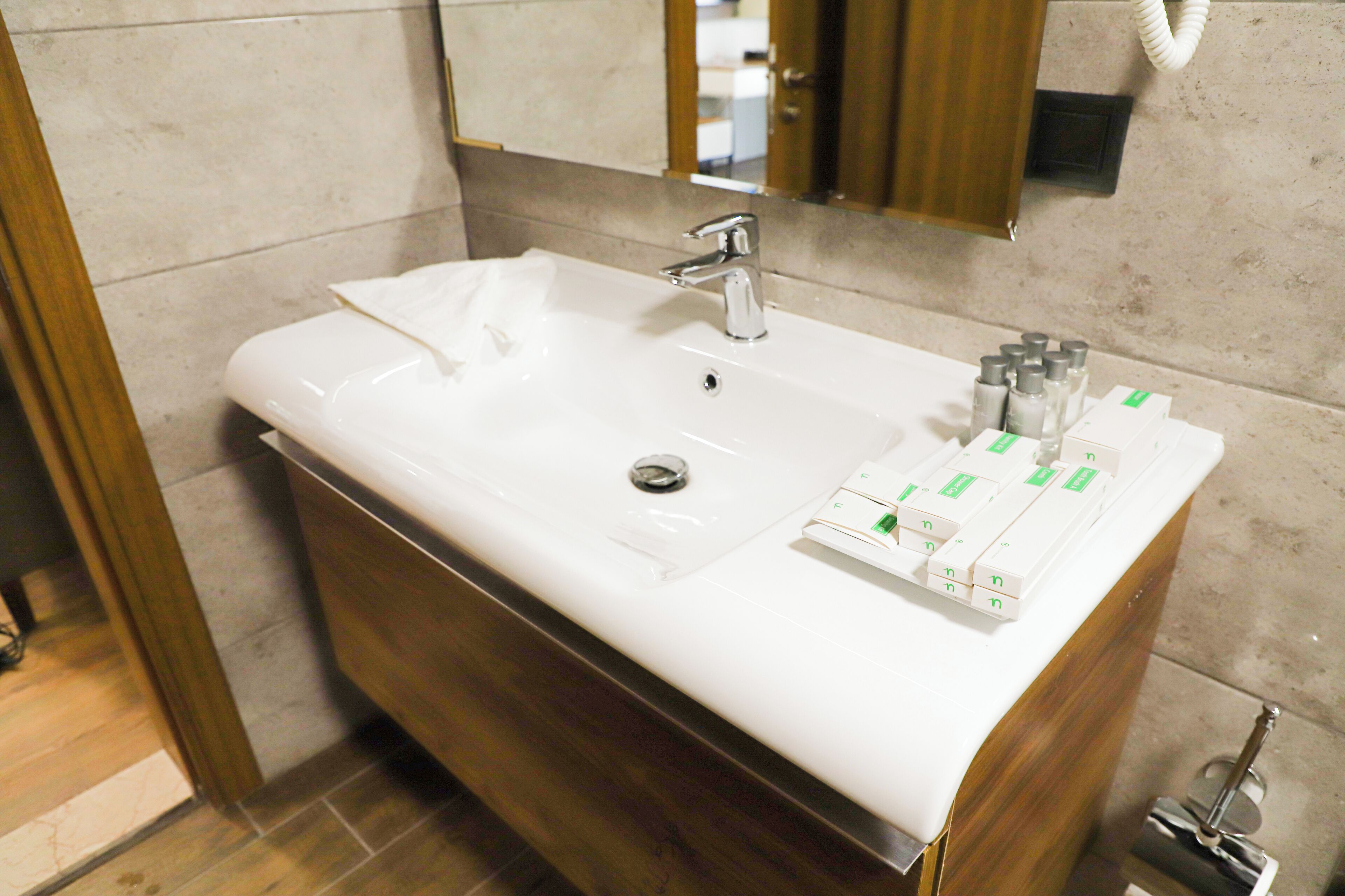 A bathroom with a white sink, a mirror, and toiletries.