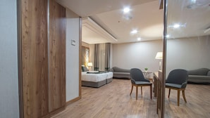 Et moderne hotelværelse med trægulv, en seng, to lænestole, et lille bord og en lampe.