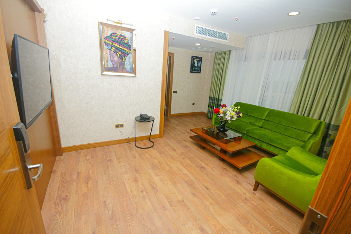 A living room with a green sofa, a wooden coffee table, and a flat-screen TV mounted on the wall.