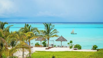 Een privéstrand, wit zand, ligstoelen aan het strand, parasols