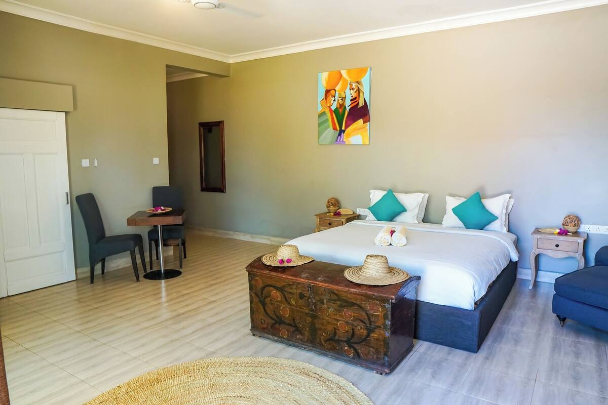 A bedroom with a bed, bedside tables, a desk, a chair, and a decorative chest.