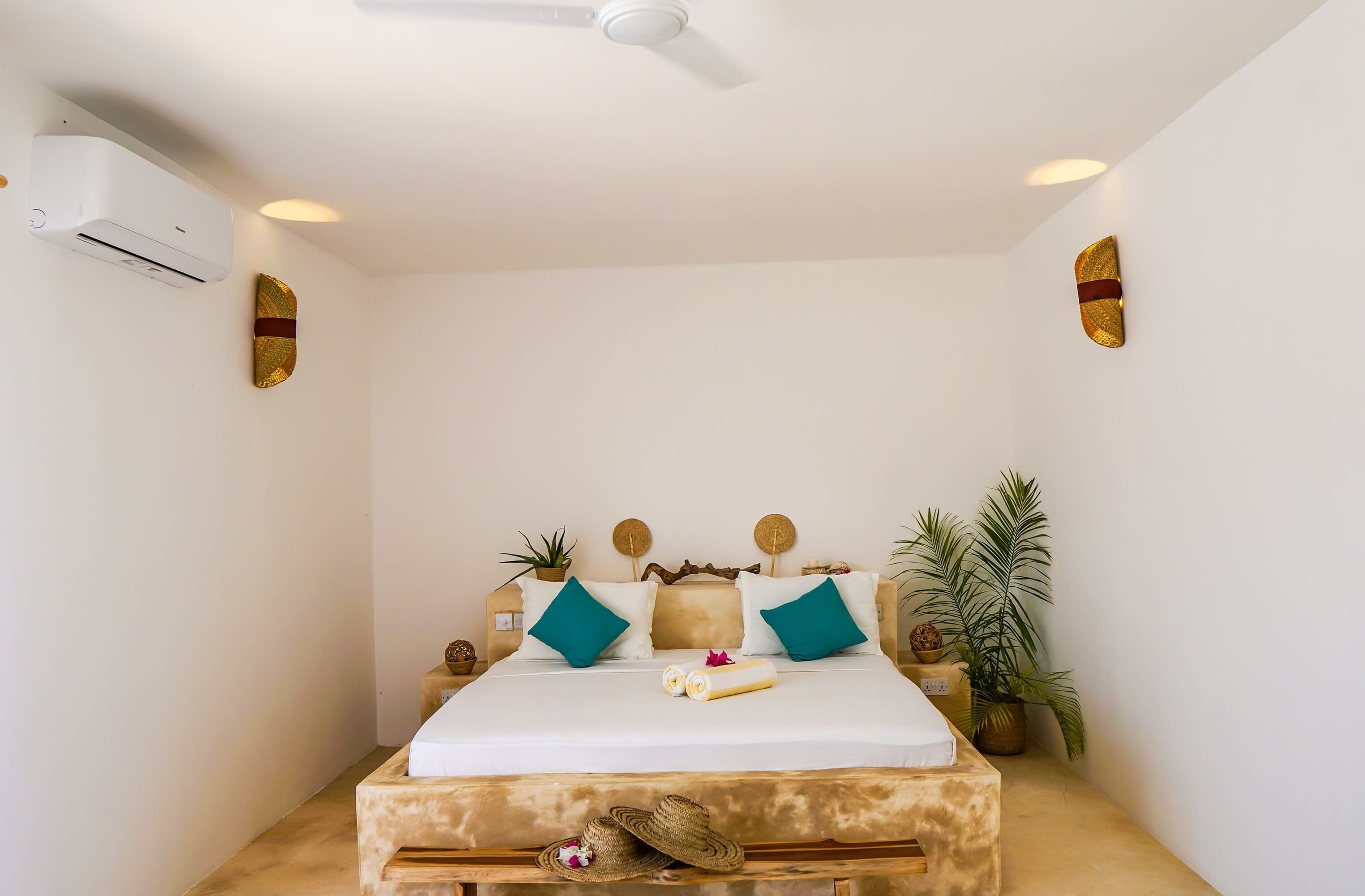 A neatly arranged bedroom with a bed, pillows, a ceiling fan, and wall-mounted decor.