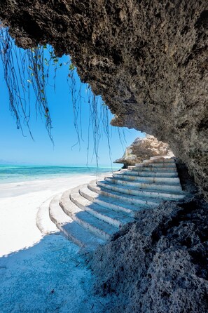 Privat strand, hvit sand, solsenger og parasoller