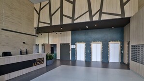Eine geräumige Lobby mit einer Rezeption, einer großen Sitzecke und drei Türen.