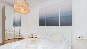 Ein modernes Schlafzimmer mit einem großen Bett, einem Nachttisch, einer Hängeleuchte und einer Wand mit einem großen Gemälde.