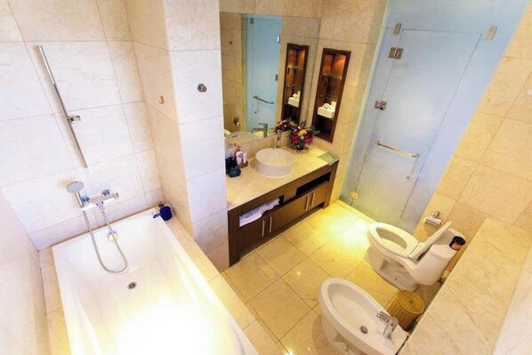 A modern bathroom with a bathtub, a toilet, a bidet, and a vanity with a mirror.