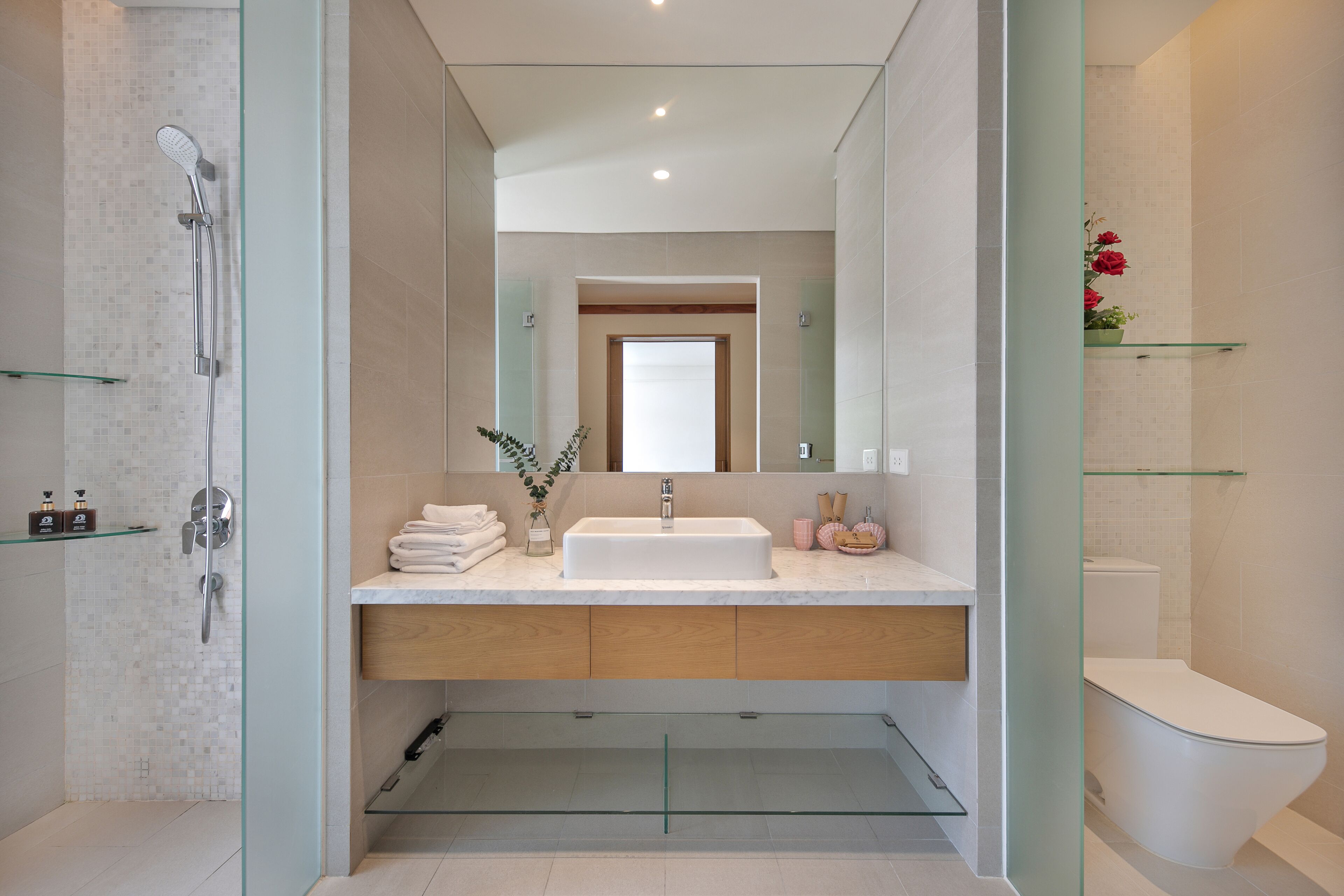 Un baño moderno con cabina de ducha de vidrio, un lavabo blanco y un inodoro.