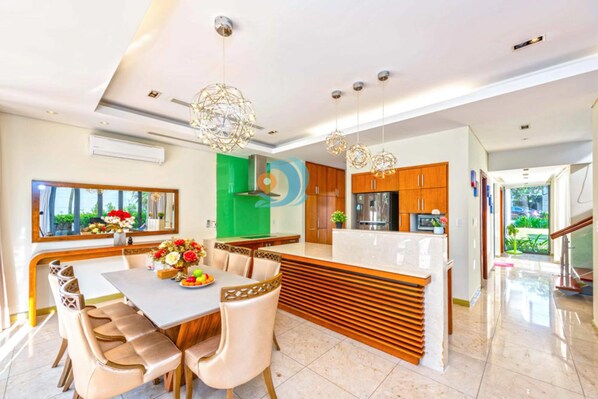 Une cuisine moderne dotée d’un îlot central, de meubles en bois et de luminaires suspendus.