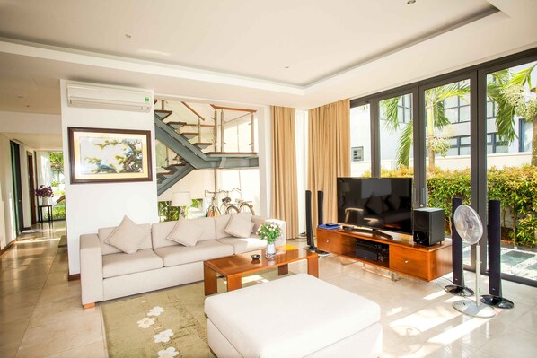 A modern living room with a sofa, coffee table, TV, and a staircase.