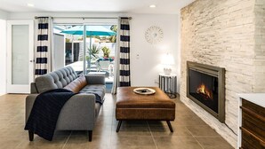 Un salón con chimenea, un sofá, una mesa de centro y vistas al exterior.