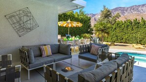 An outdoor seating area with a pool, a dining table, and chairs. - Blue Door at Indian Canyons – Mid-Century Retreat with Pool, Spa, Golf Course and Mountain Views (Palm Springs)