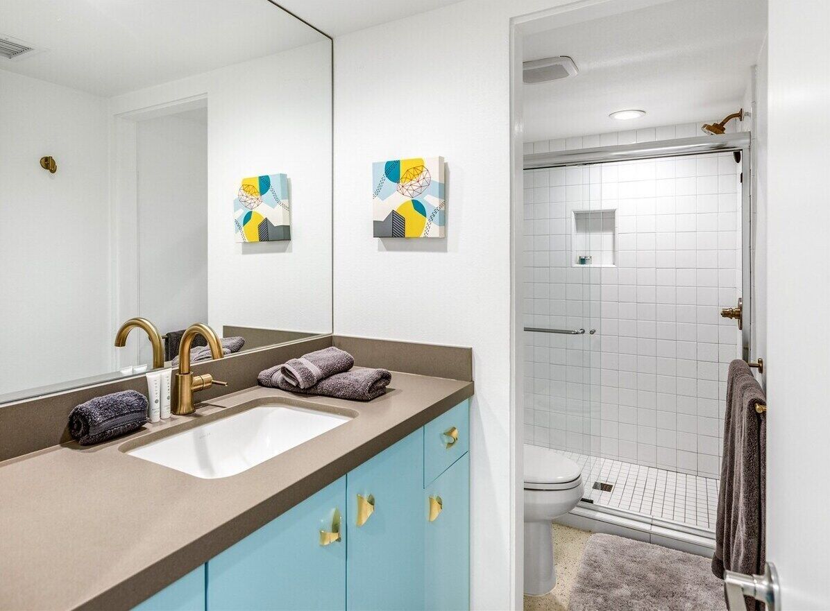 A bathroom with a sink, mirror, and shower.