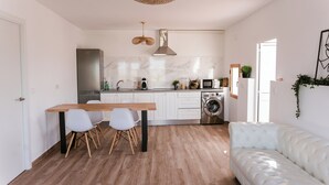 Een moderne keuken met witte kasten, een houten eettafel en een witte bank.