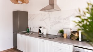 Een moderne keuken met een marmeren spatwand, roestvrijstalen apparatuur en een hanglamp.