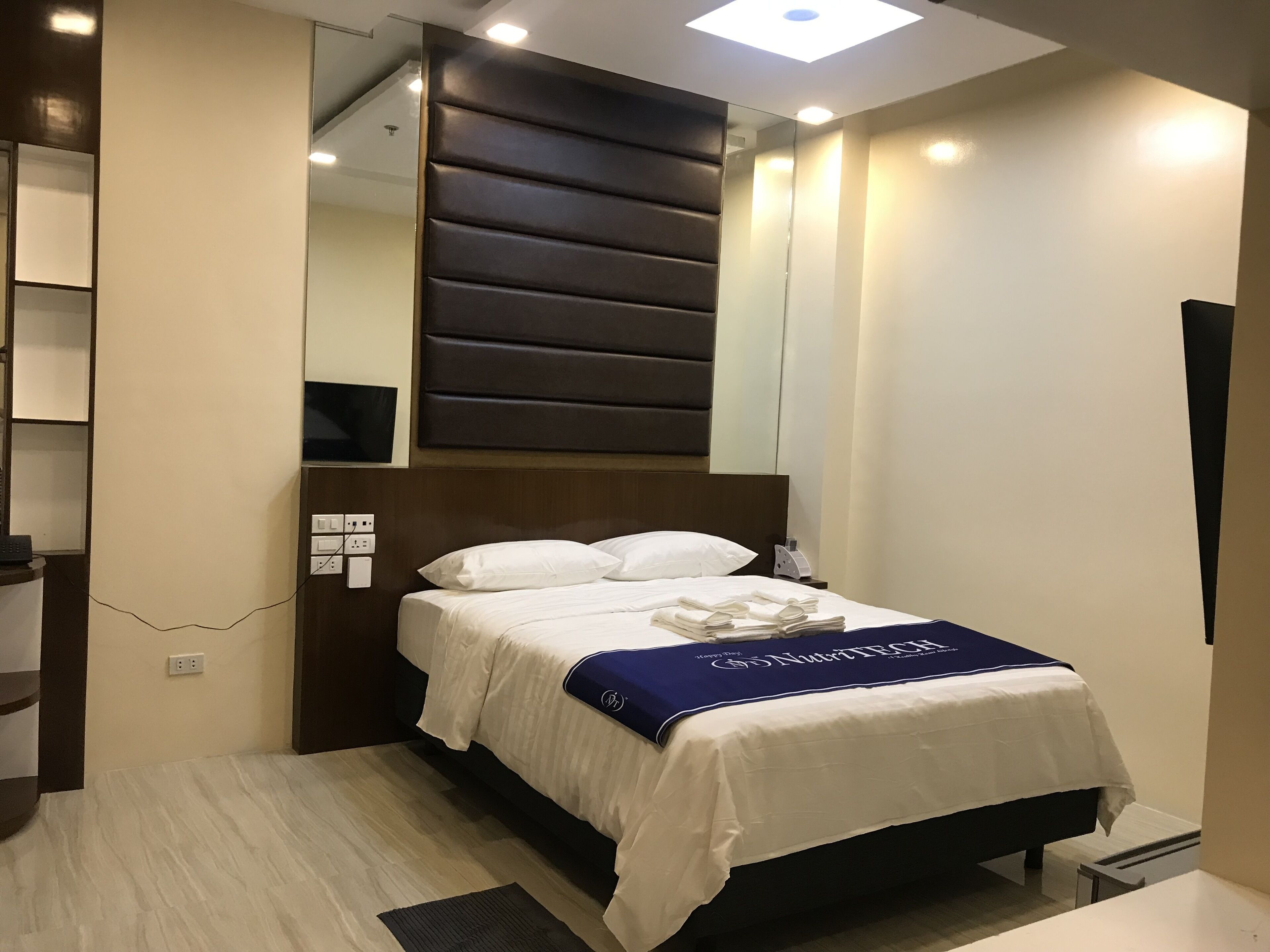 A modern hotel room with a large bed, a flat-screen TV, and a bedside table.