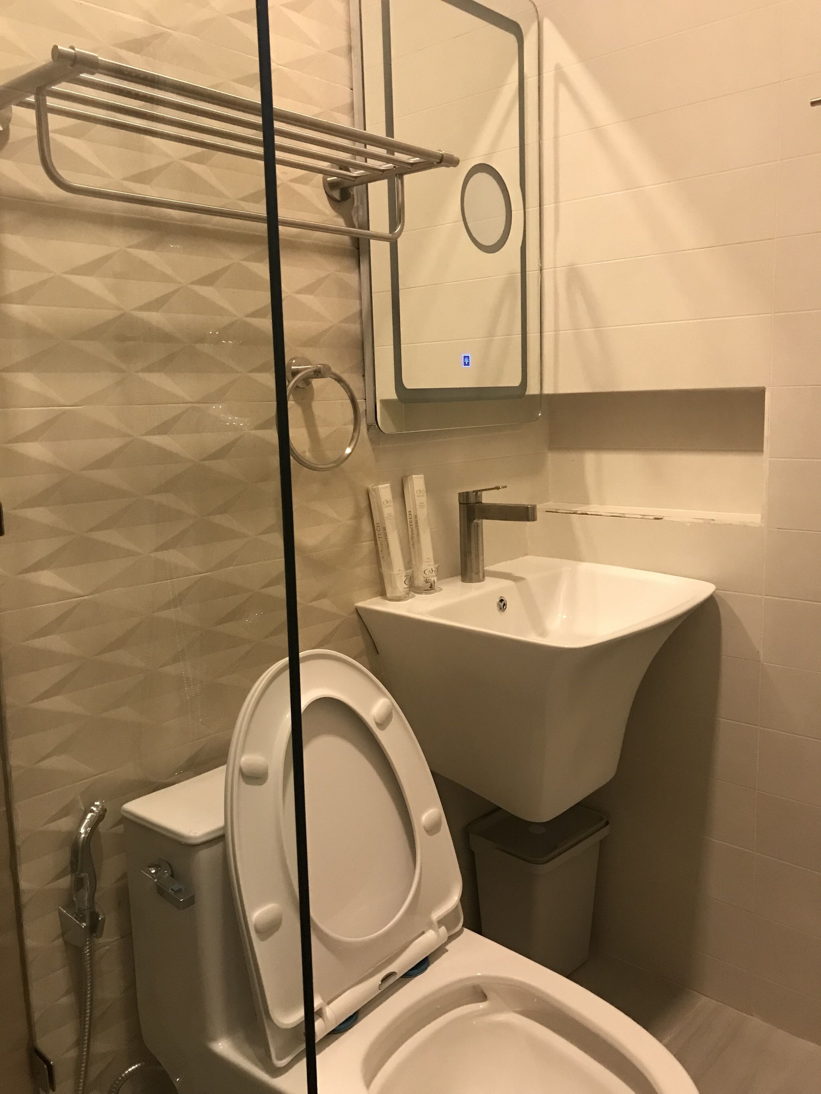 A bathroom with a toilet, bidet, sink, and a towel rack.