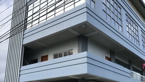 A multi-story building with large windows, a garage with closed shutters, and a visible staircase. - NutriTECH Hotel and Events (Calapan)