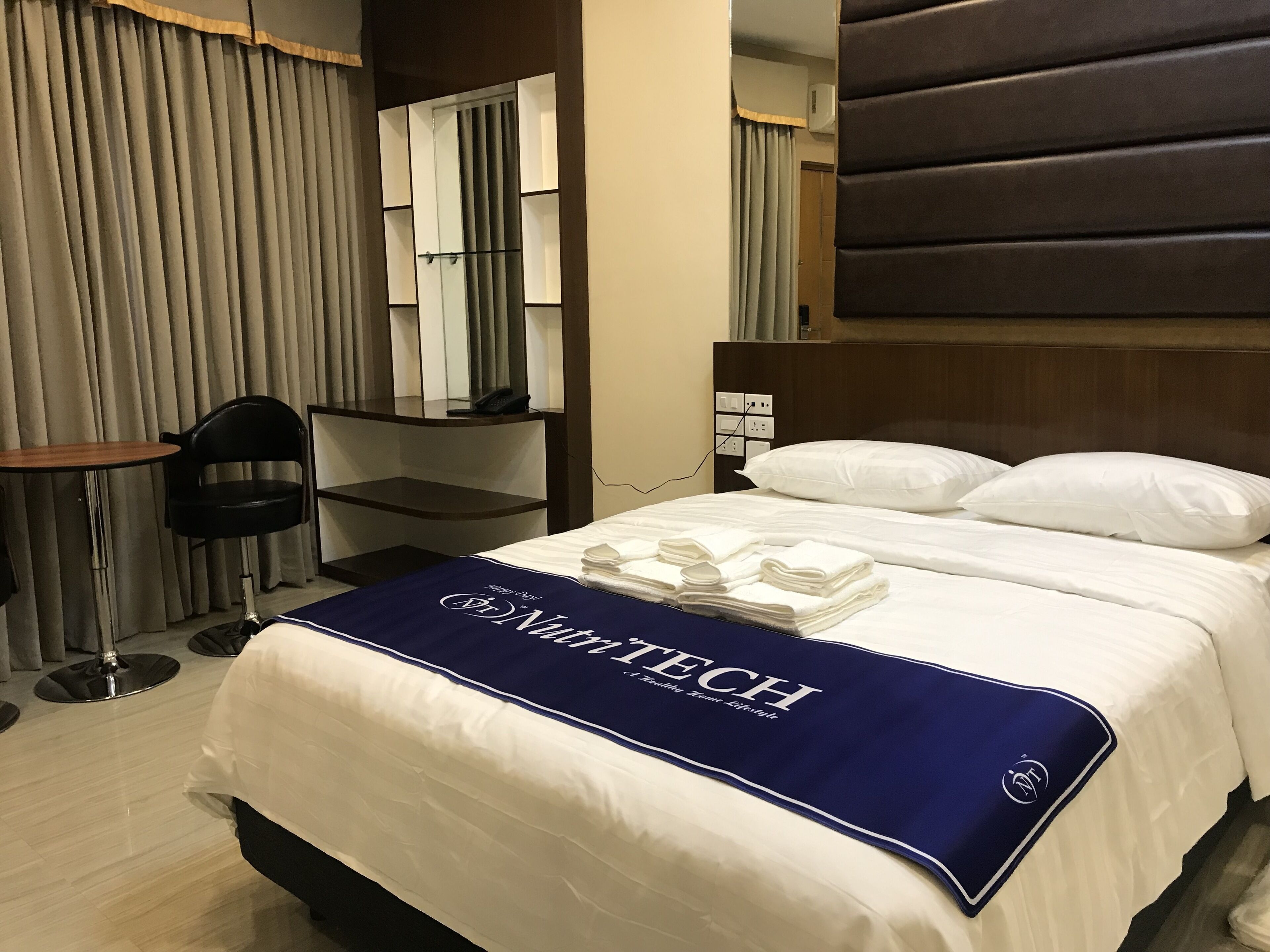 Une chambre d’hôtel avec un lit bien fait, un bureau avec une chaise et un grand miroir.