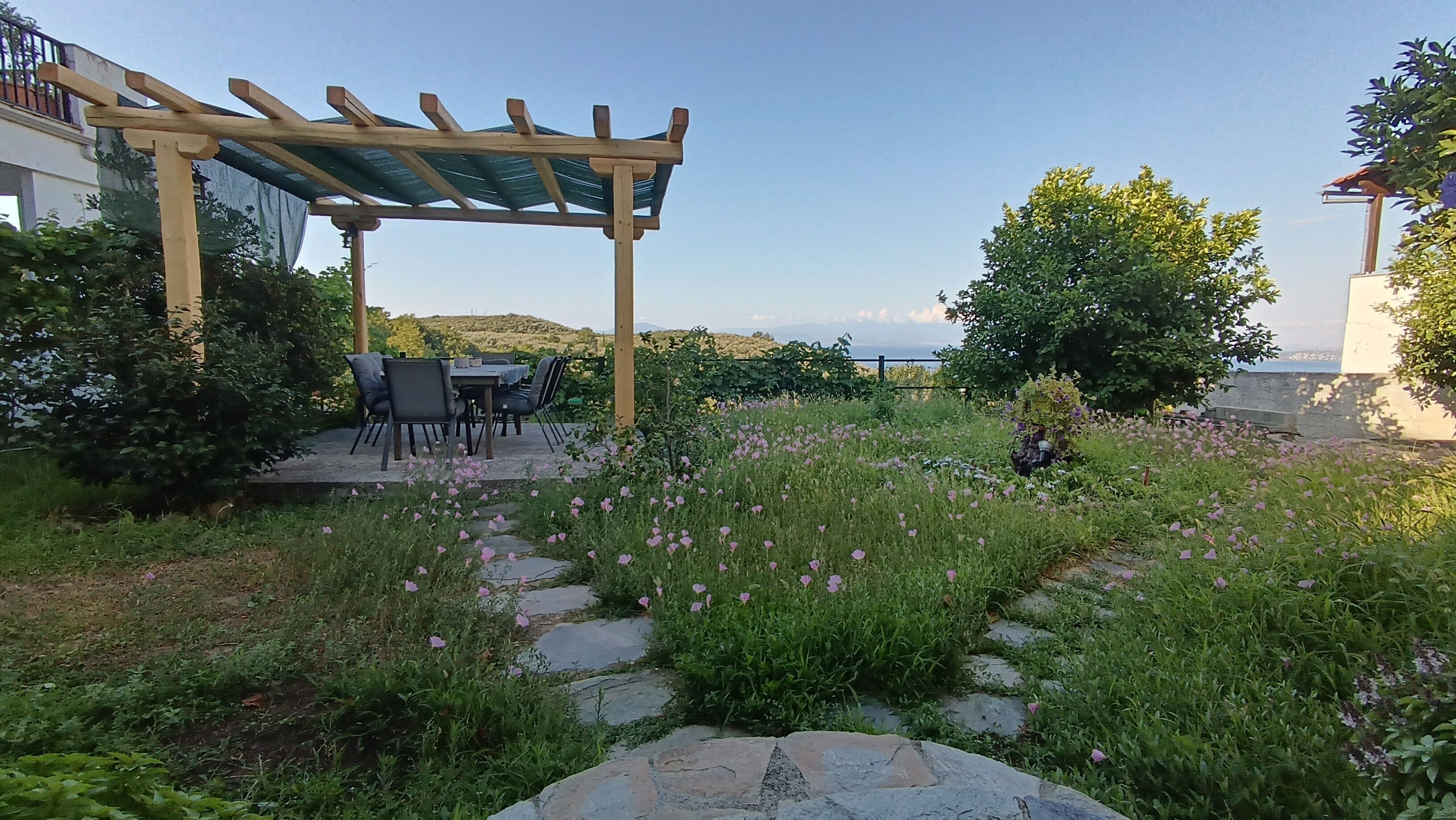 Un patio aménagé avec une pergola, des sièges d’extérieur et un chemin en pierre.