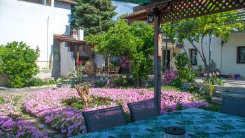 A patio with a table set for dining, surrounded by a garden with flowering plants.