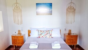 A neatly made bed with two pillows, a wooden headboard, and a wall-mounted macrame light fixture. - Mikros Paradisos Pelion (Volos)