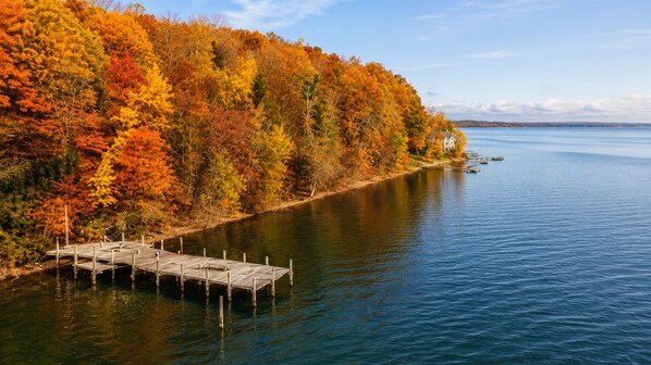 A dock extending into calm water, surrounded by dense autumn foliage.