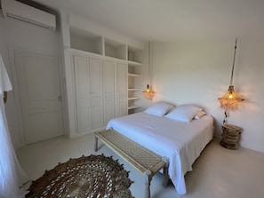 Ein Schlafzimmer mit einem Bett, zwei Hängelampen, einer Bank und einem Kleiderschrank.