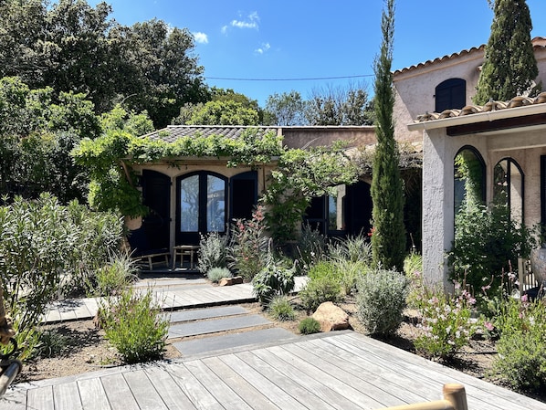 Ein Garten mit einer Holzterrasse, einer Pergola und verschiedenen Pflanzen.