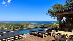 Eine Holzterrasse mit Pool, Liegestühlen und einem Tisch.