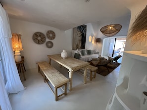 Ein gemütliches Wohnzimmer mit einem Holztisch, Bänken, einer Couch und einem großen Gemälde an der Wand.
