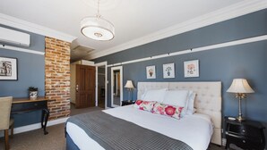 A bedroom with a large bed, a desk, a chair, and a brick accent wall. - Enfield House (Menah)