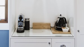 A kitchen with a coffee maker, a kettle, and a wine glass on the counter. - Enfield House (Menah)