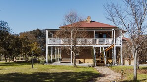 A two-story house with a balcony, a brick exterior, and a red roof. - Enfield House (Menah)