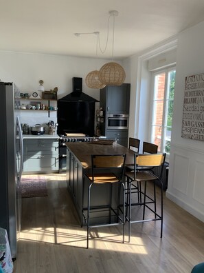 Una cocina moderna con una isla central, electrodomésticos negros y una zona de comedor con sillas de metal.