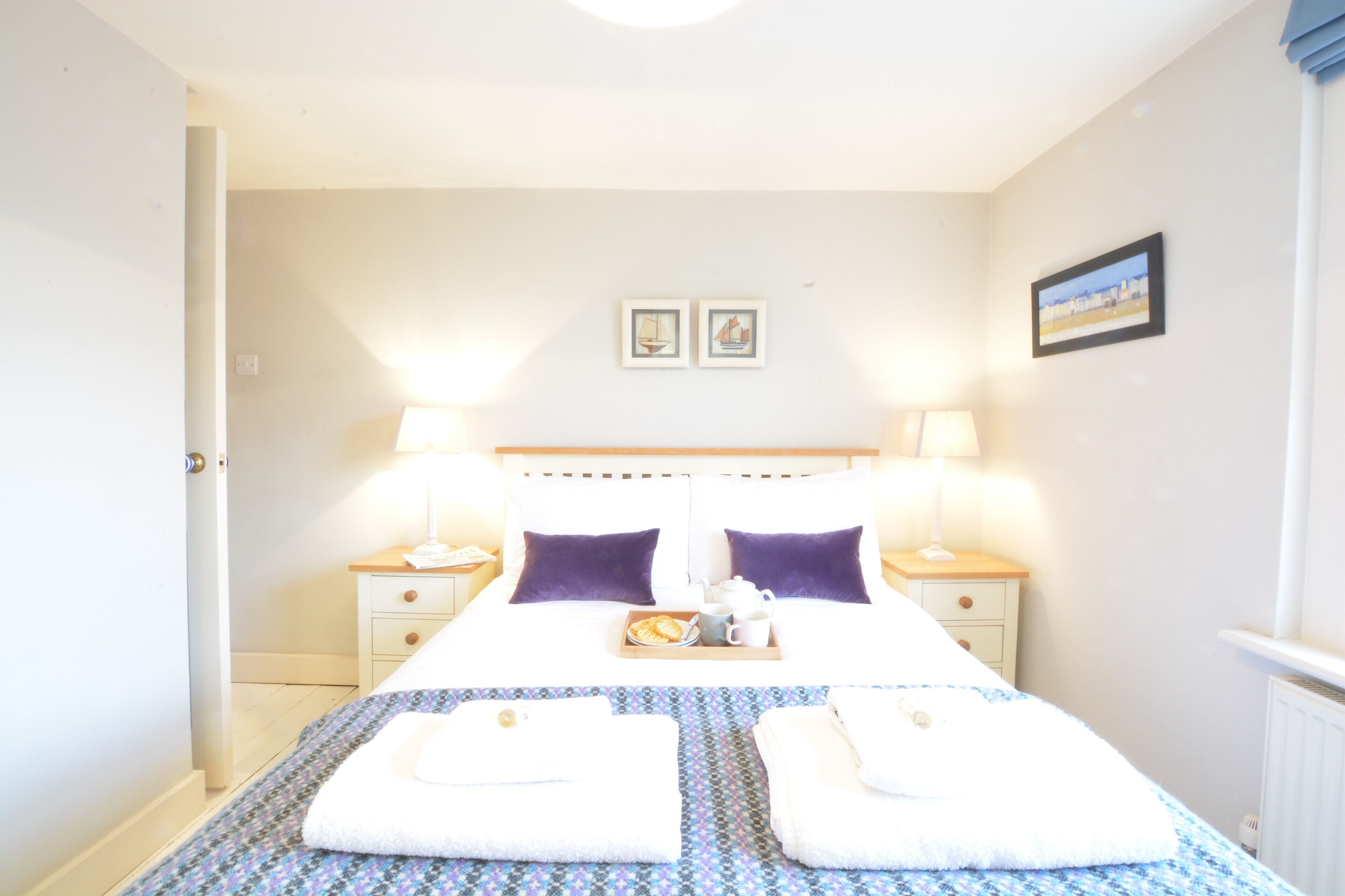 Habitación de hotel con cama, dos mesitas de noche, una lámpara y un cuadro en la pared.
