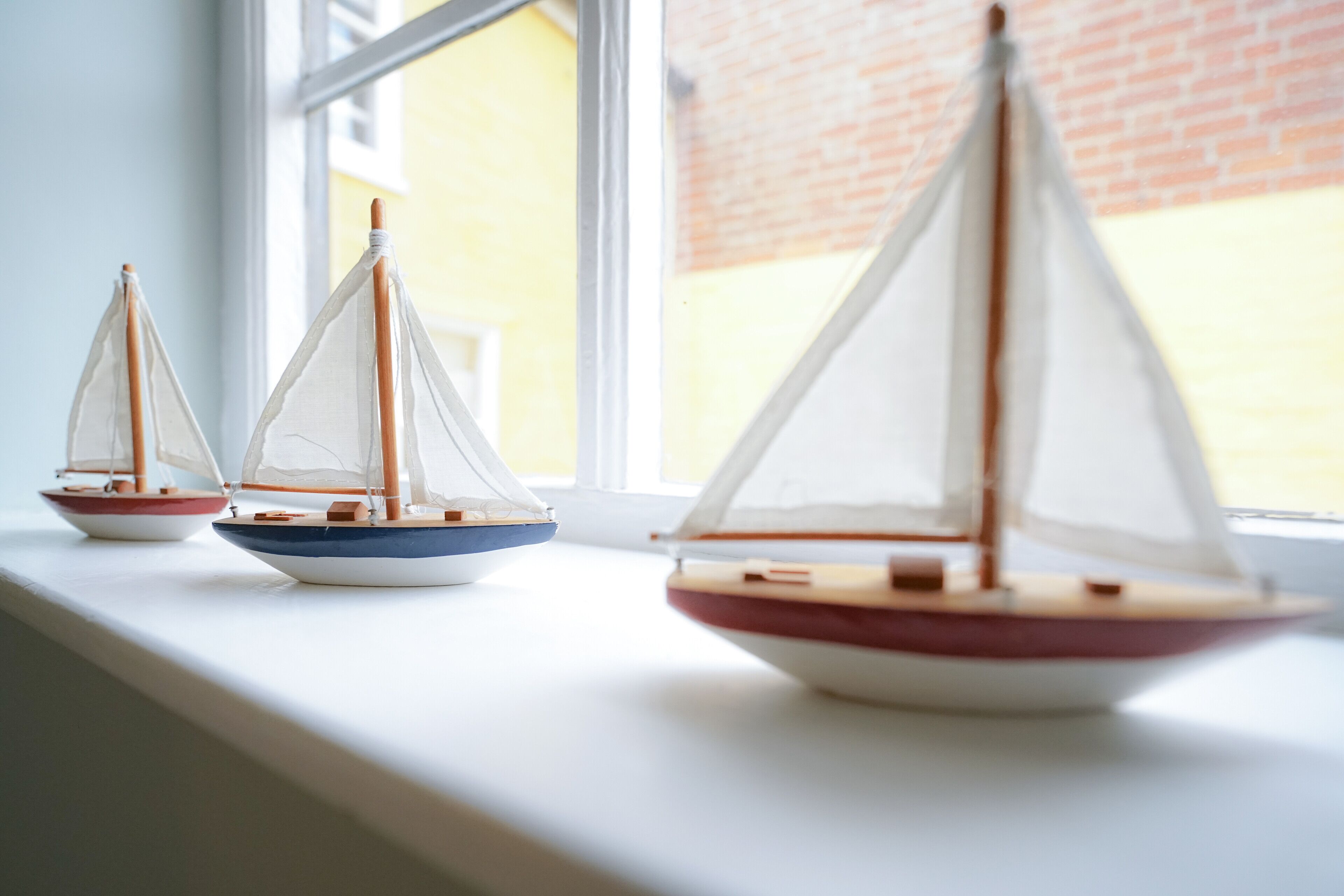 Three model sailboats on a windowsill.